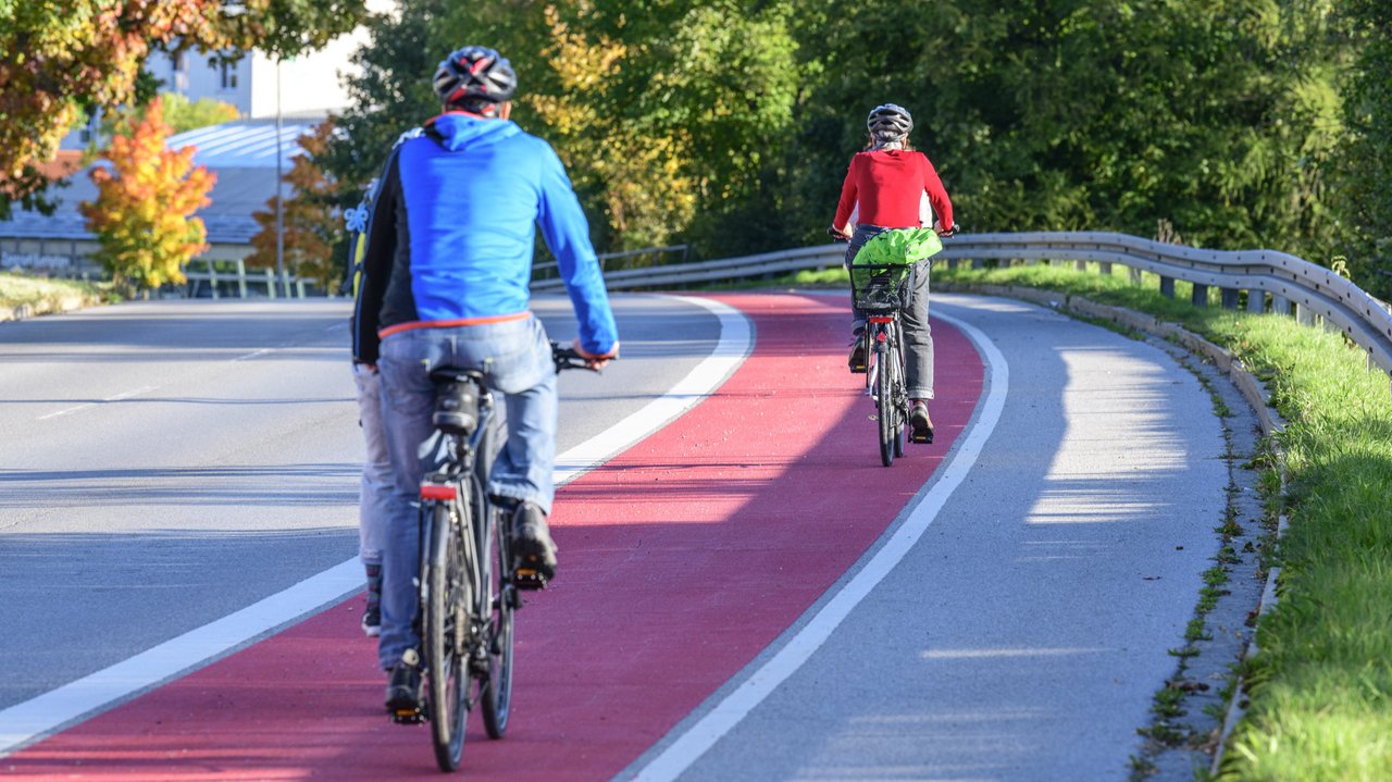 Zwei Fahrradfahrer fahren auf einem rot gekennzeichneten Radweg. man sieht sie von hinten