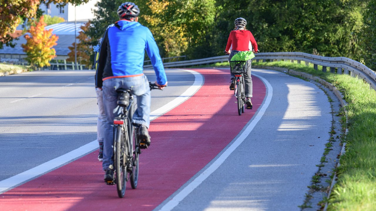 Zwei Fahrradfahrer fahren auf einem rot gekennzeichneten Radweg. man sieht sie von hinten