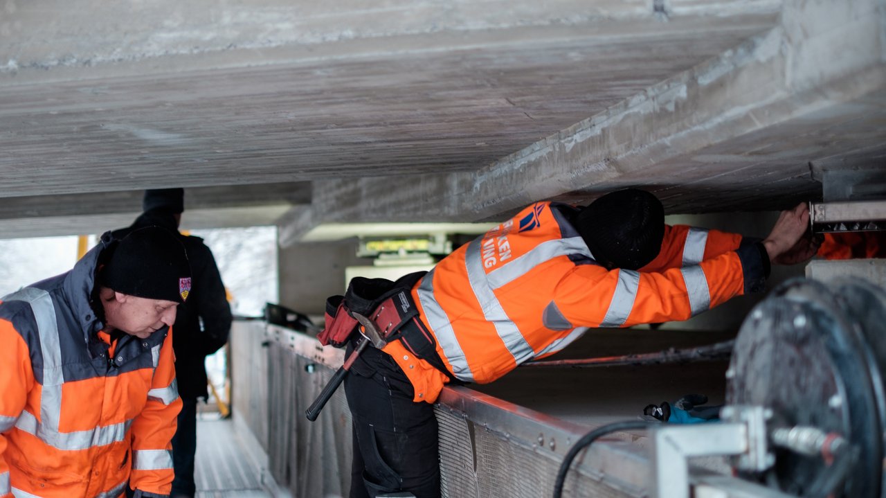 Zwei Arbeiter prüfen eine Brücke von unten