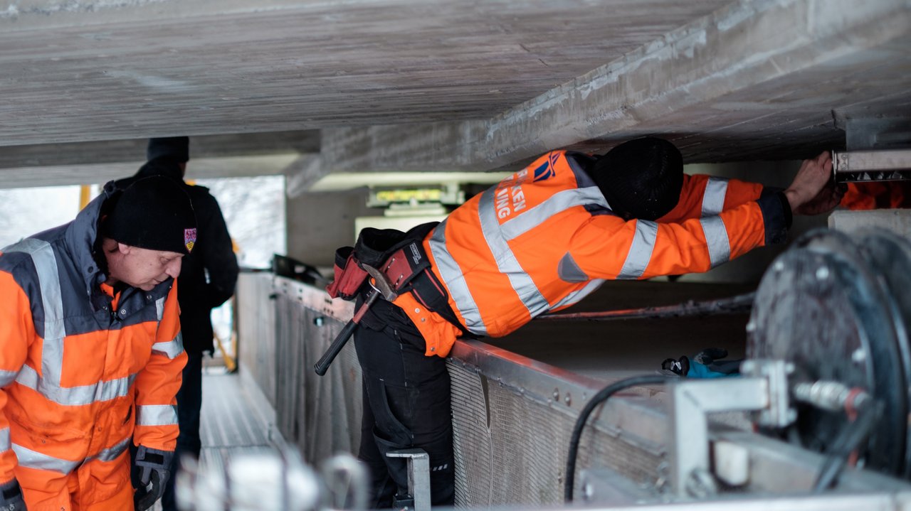 Zwei Arbeiter prüfen eine Brücke von unten