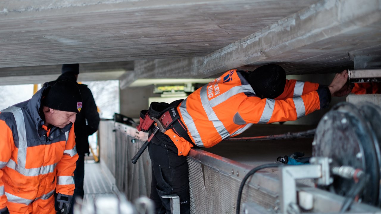 Zwei Arbeiter prüfen eine Brücke von unten