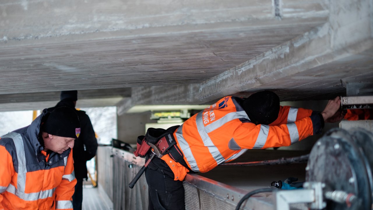 Zwei Arbeiter prüfen eine Brücke von unten