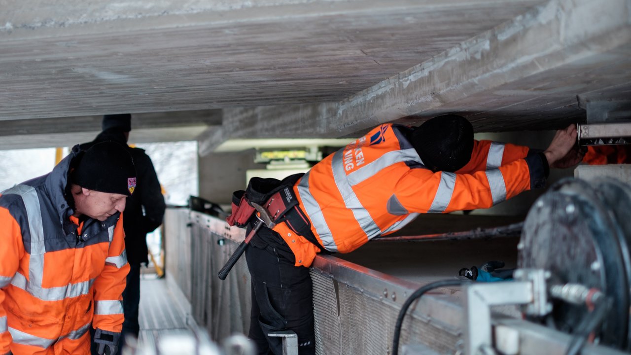 Zwei Arbeiter prüfen eine Brücke von unten