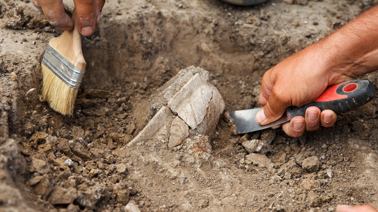 Person gräbt ein archäologisches Artefakt aus der Erde