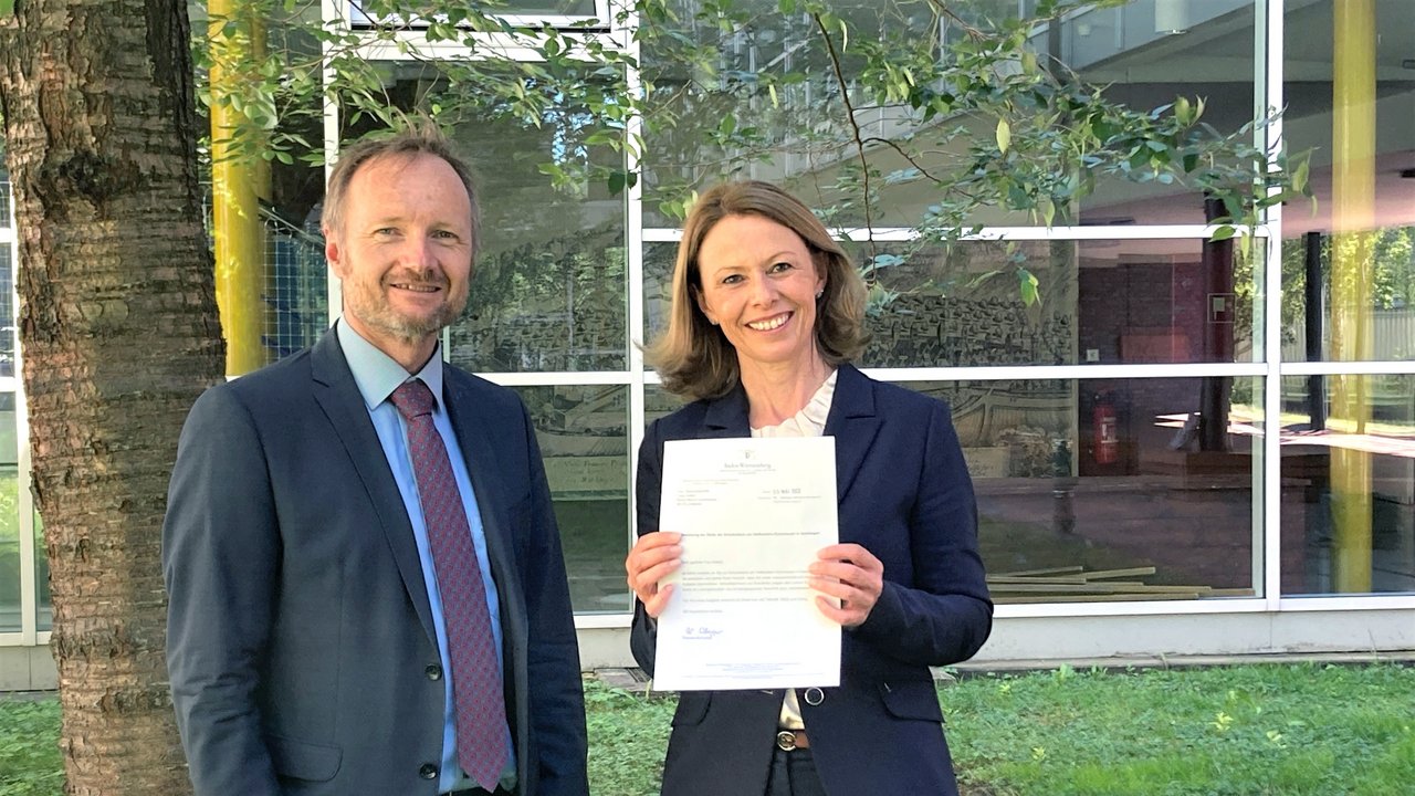 -	Bild: Dr. Thomas Hölz (links), Leiter des Gymnasialreferats am Regierungspräsidium Stuttgart, überreicht Tanja Keifert (rechts) das Bestellungsschreiben von Kultusministerin Theresa Schopper