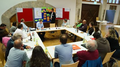 Mehrere Personen sitzen im Gespräch um einen Tisch