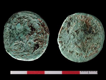 Eine Bronzemünze (unrestauriert, 1 Dupondius = ½ Sesterz) aus dem Bereich der römischen Straße. Schemenhaft ist auf der Vorderseite (rechts) das Abbild eines Kaisers (vermutlich Kaiser Domitian) zu erkennen.