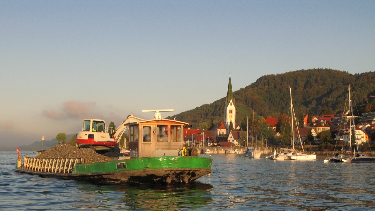 Bild zeigt ein Schiff auf dem See, im Hintergrund eine Stadt