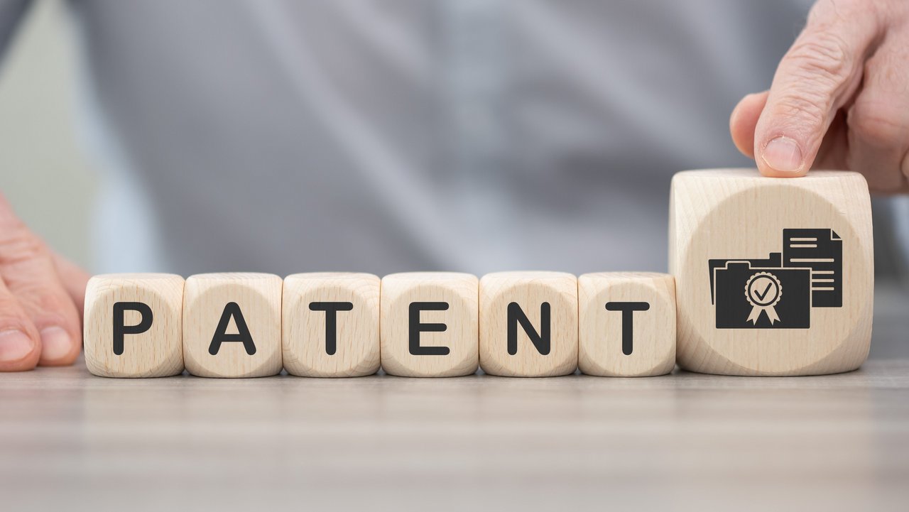 Sechs Würfel nebeneinander, die das Wort Patent bilden, daneben ein größerer Würfel