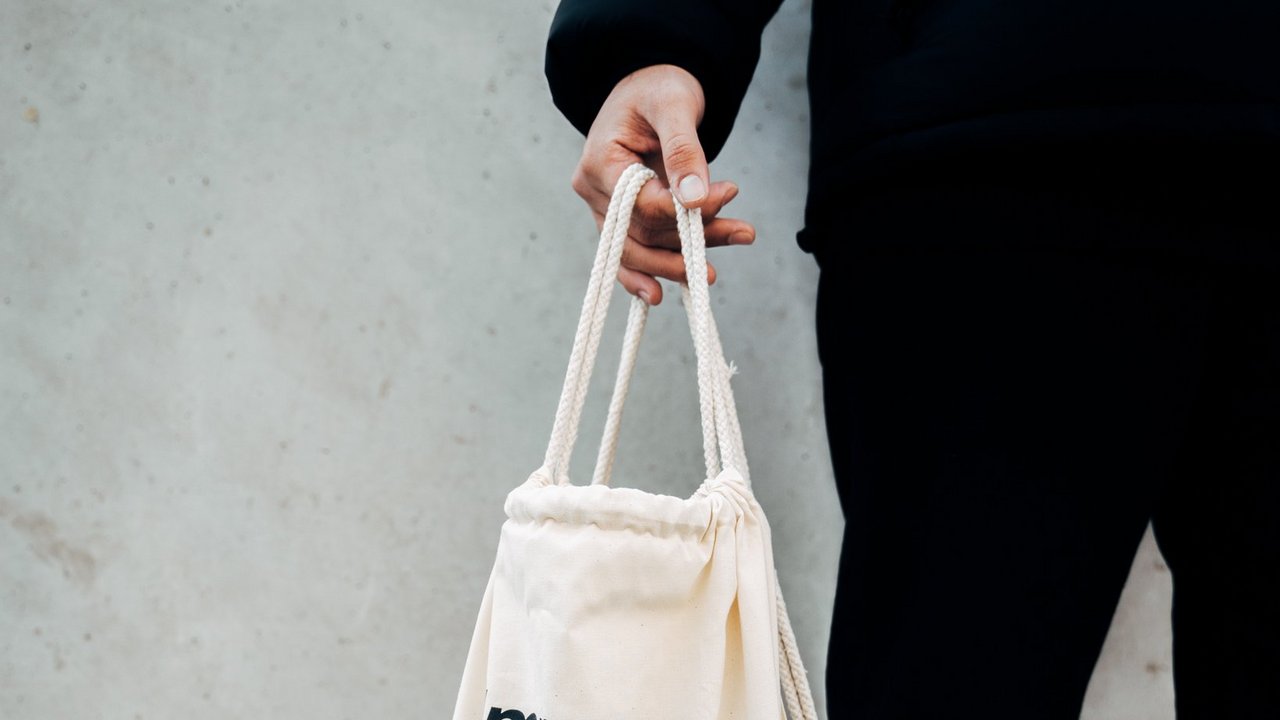 Jugendlicher hält einen Stoffbeutel mit der Aufschrift Immer schön in Bewegung bleiben