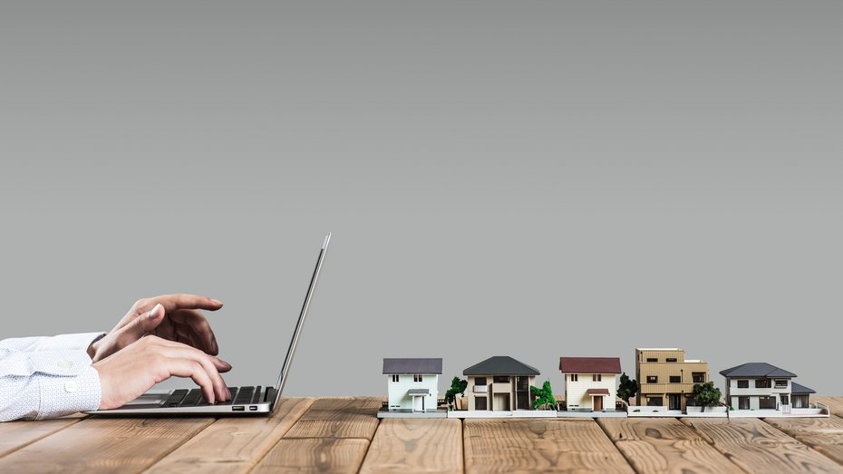 Person am Laptop vor sich 5 Häuser Person am Laptop vor sich 5 Häuser