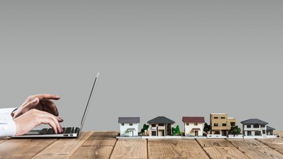 Person am Laptop vor sich 5 Häuser