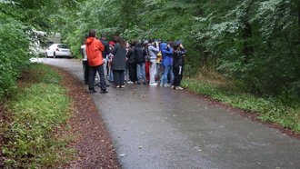 Regierungspräsidentin Bay steht mit Kindern auf einem Waldweg