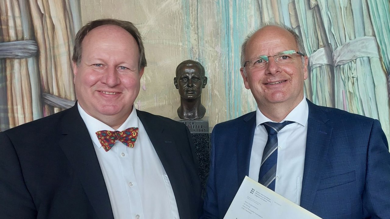 Jörg Brehmer (links), Schulreferent am Regierungspräsidium Stuttgart, überreicht Ulf Hannig (rechts) das Bestellungsschreiben von Kultusministerin Theresa Schopper. 