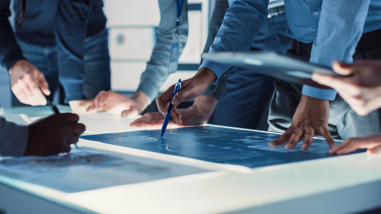 Ingenieure, Wissenschaftler und Entwickler an einem beleuchteten Arbeitstisch
