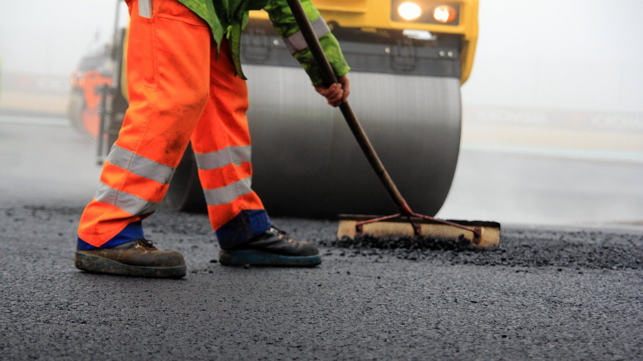 Bild zeigt Straßenwalze und Bauarbeiter mit Besen bei der Asphaltfertigung Bild zeigt Straßenwalze und Bauarbeiter mit Besen bei der Asphaltfertigung