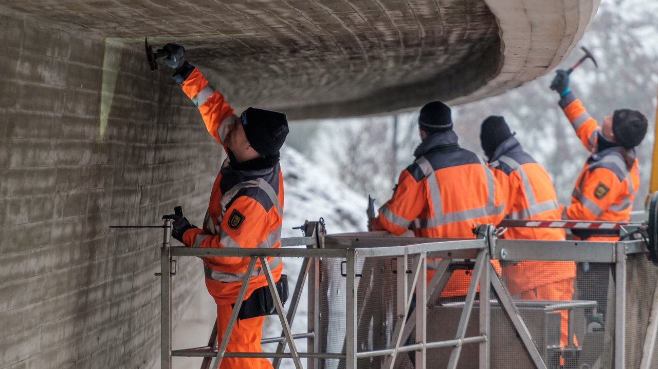 Vier Arbeiter prüfen eine Brücke