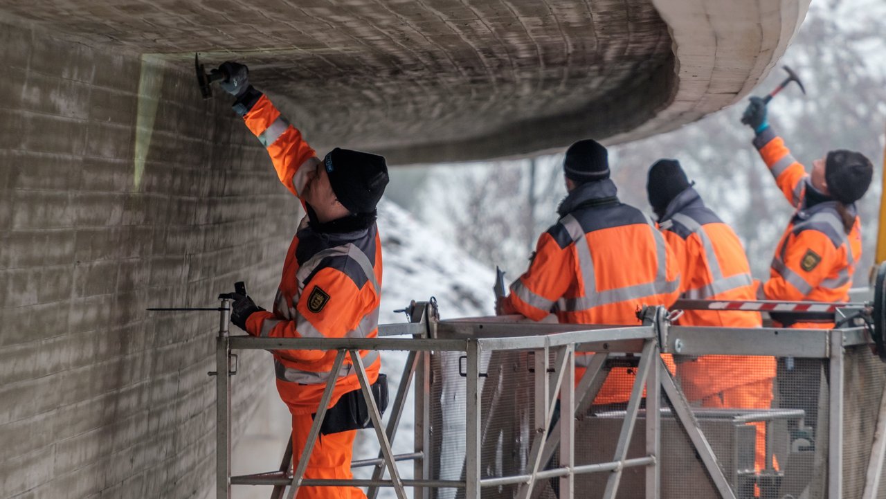 Vier Arbeiter prüfen eine Brücke