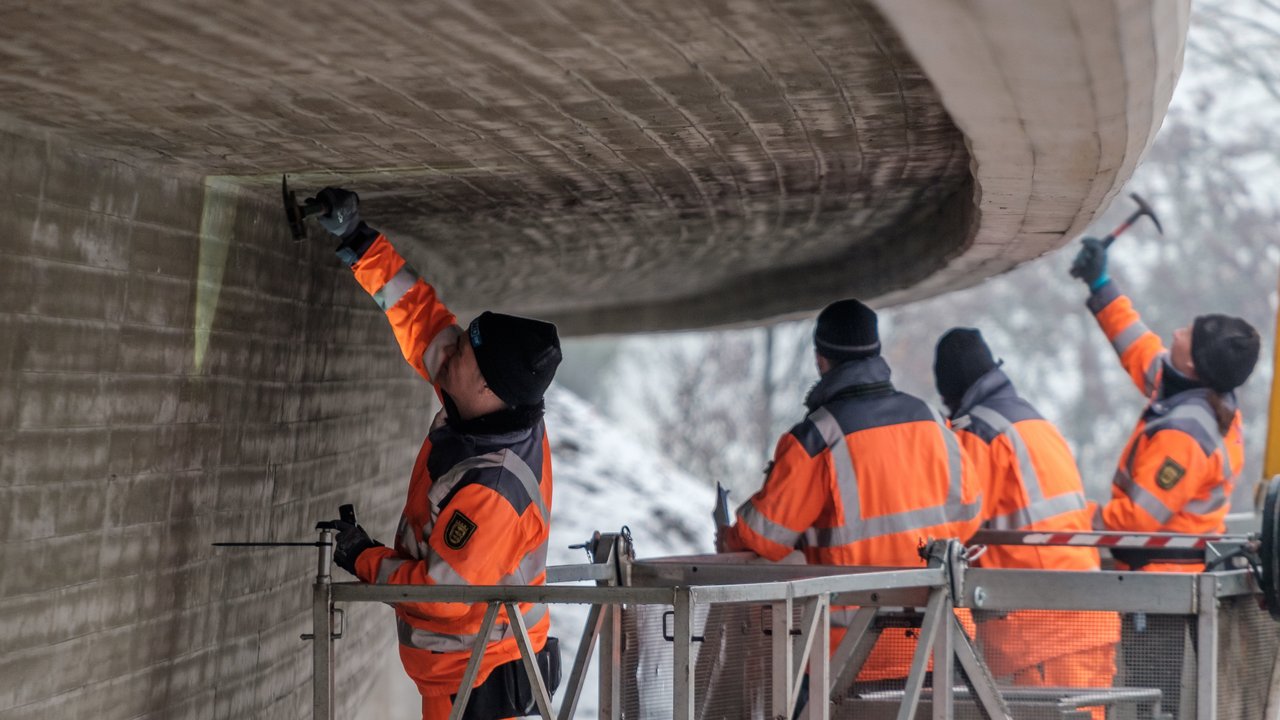 Vier Arbeiter prüfen eine Brücke