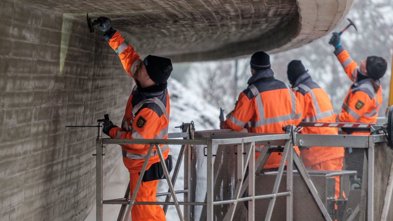 Vier Arbeiter prüfen eine Brücke