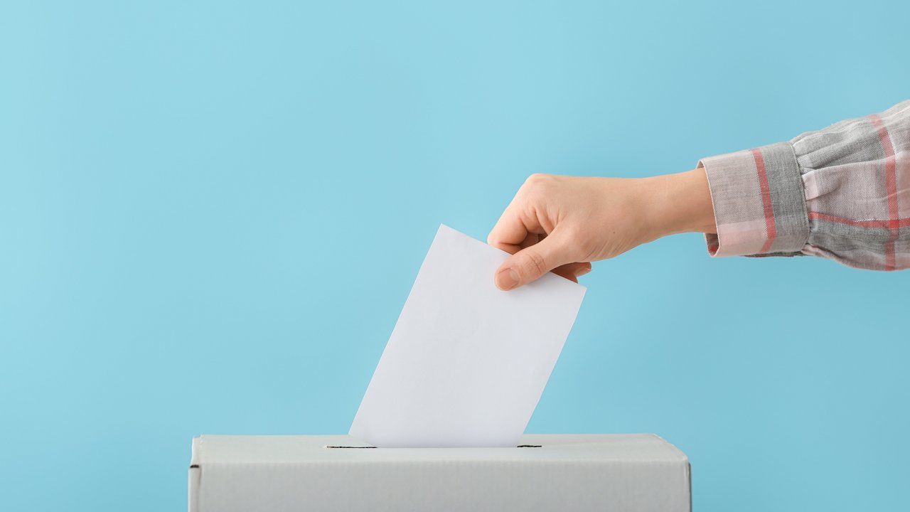 Eine Frau wirft einen Stimmzettel in eine Wahlurne