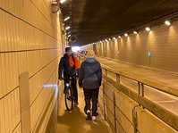 Bild zeigt den Flughafentunnel mit einem Fahrradfahrer und einer entgegen kommenden Fußgängerin