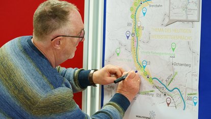 Mann zeichnet mit einem Stift auf einer Landkarte