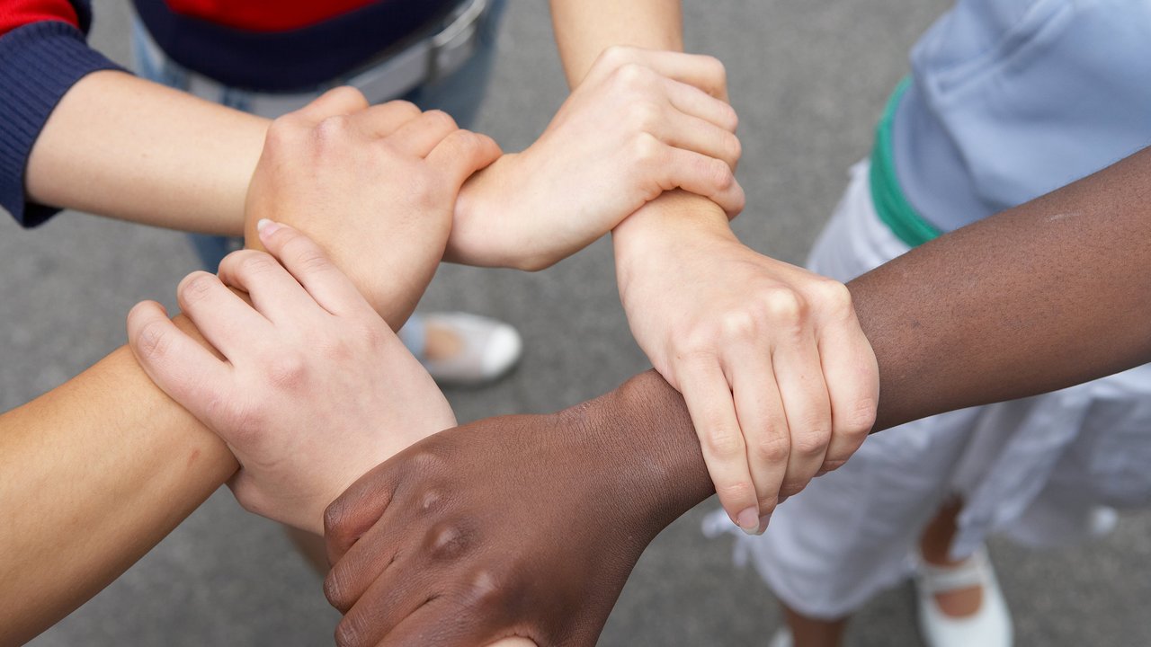 5 Hände umfassen sich und bilden einen Kreis