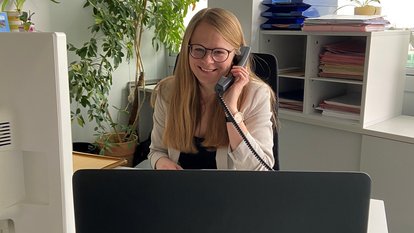 Eine Mitarbeiterin sitzt am Computer und telefoniert