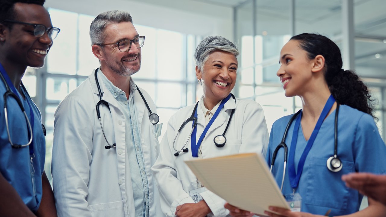 Ein Arzt, eine Ärztin, ein Pfleger und eine Pflegerin stehen beieinander und unterhalten sich