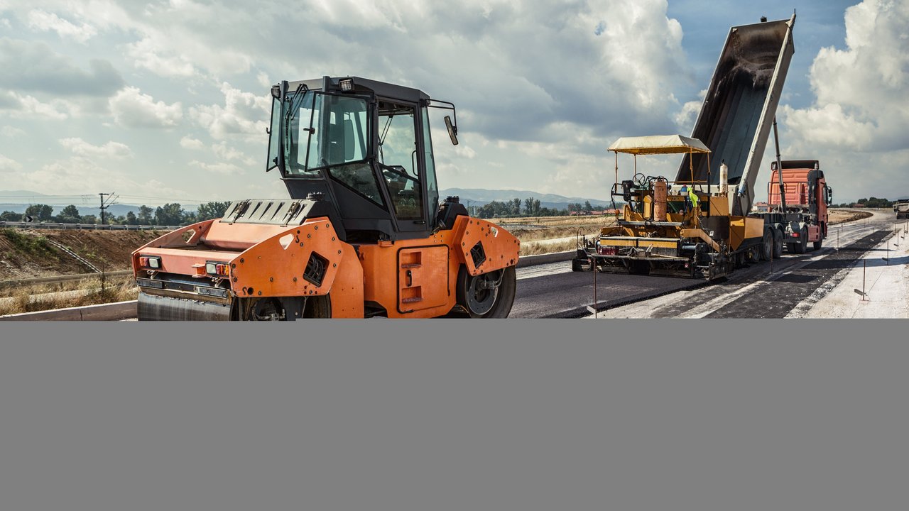 Planierraupe beim Asphaltieren einer Straße