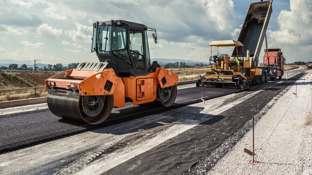 Planierraupe beim Asphaltieren einer Straße