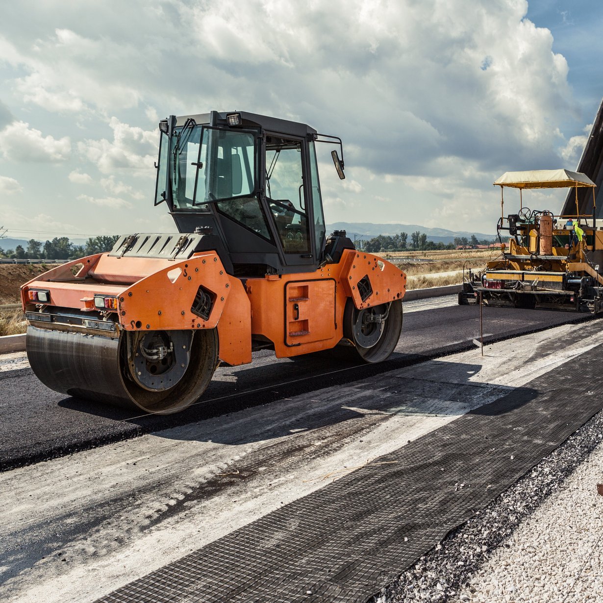 Planierraupe beim Asphaltieren einer Straße