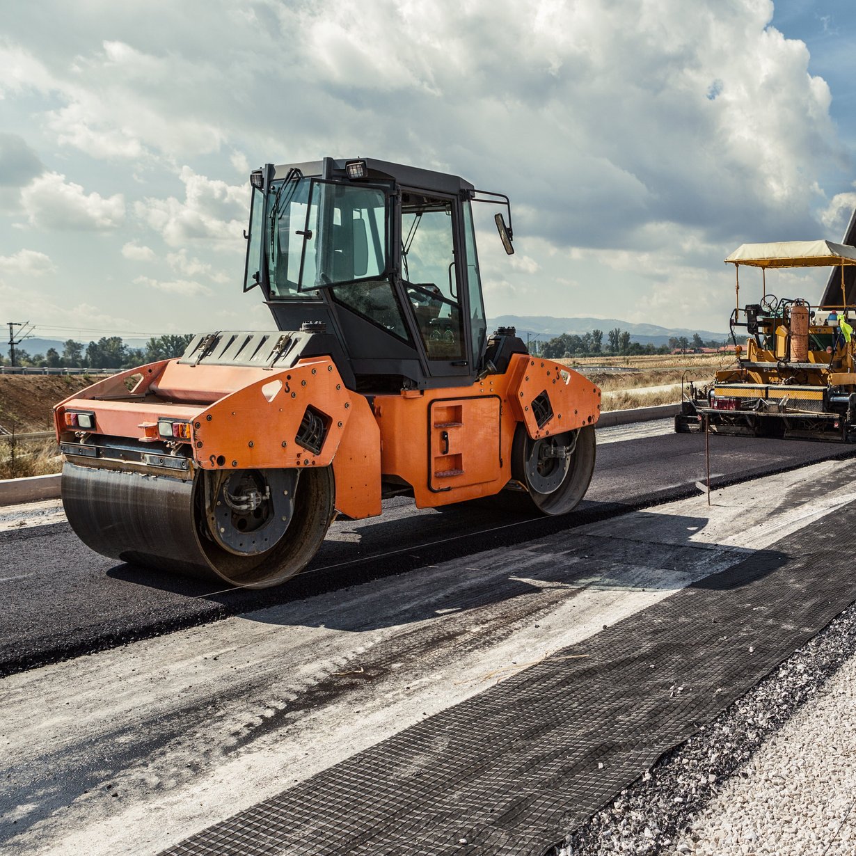 Planierraupe beim Asphaltieren einer Straße