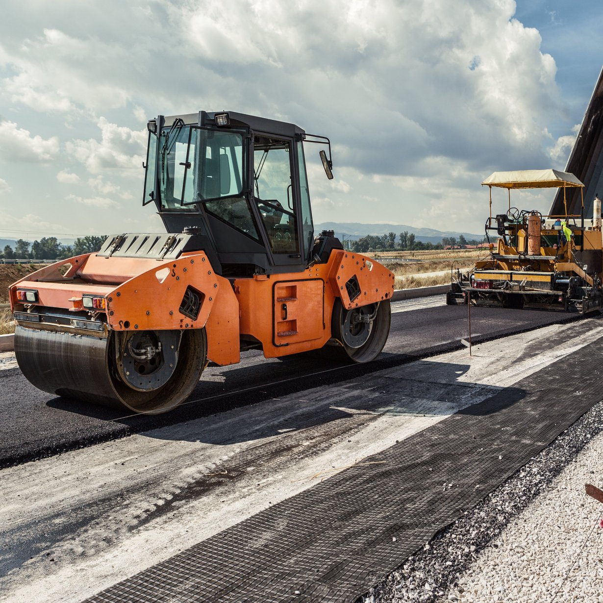 Planierraupe beim Asphaltieren einer Straße