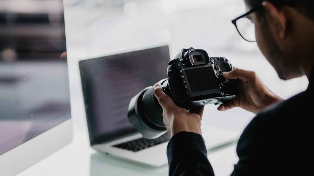 Mann hält im Büro Fotokamera in der Hand