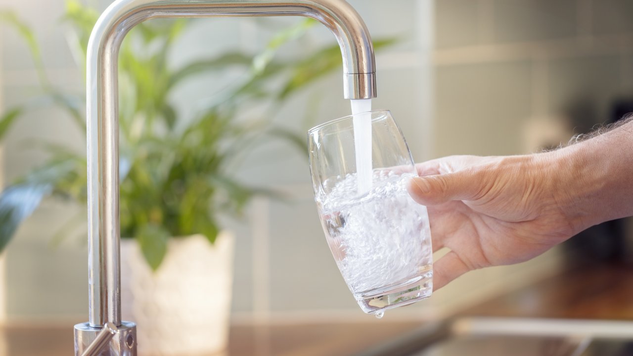 Bild zeigt ein Glas unter einem Wasserhahn