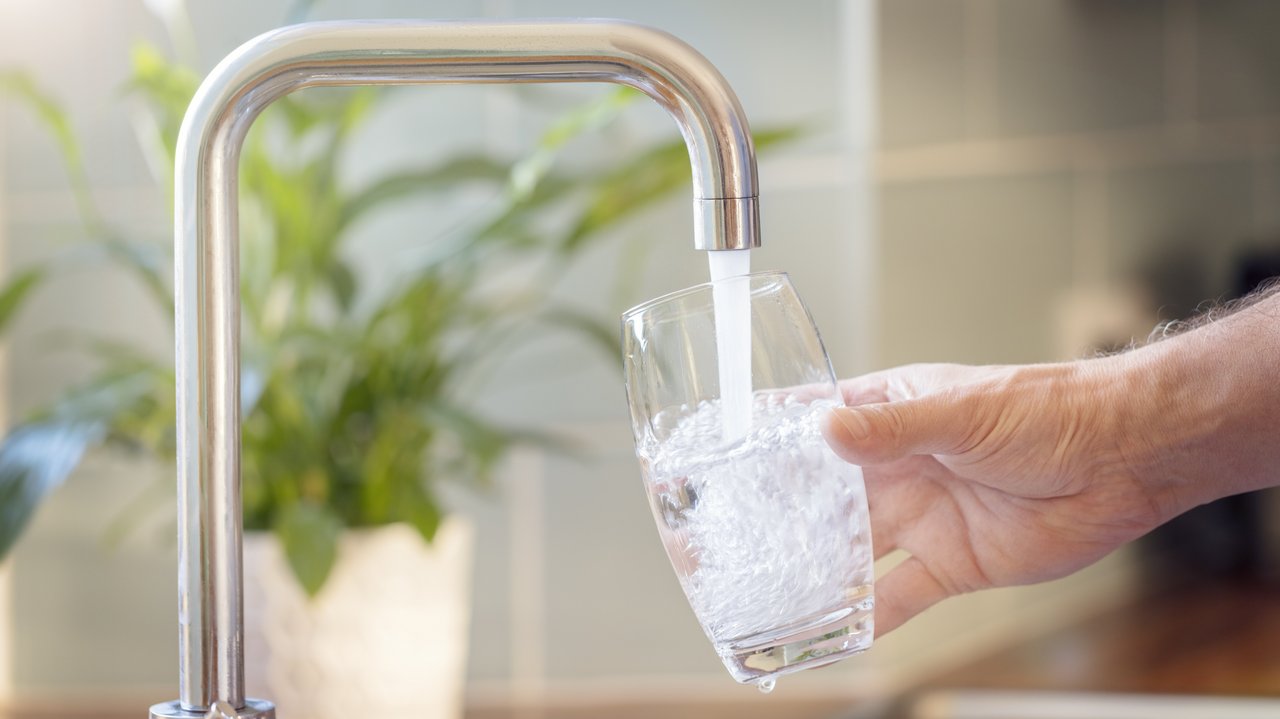 Bild zeigt ein Glas unter einem Wasserhahn