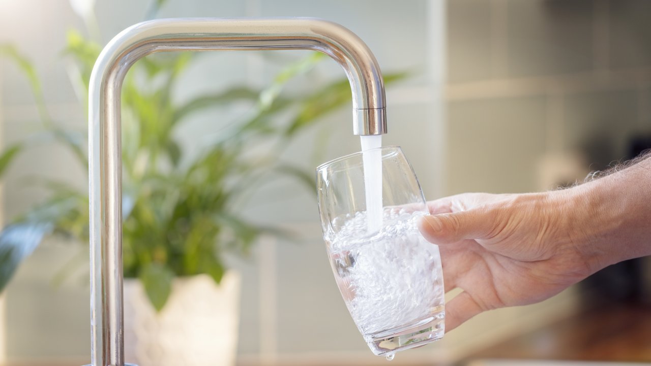 Bild zeigt ein Glas unter einem Wasserhahn