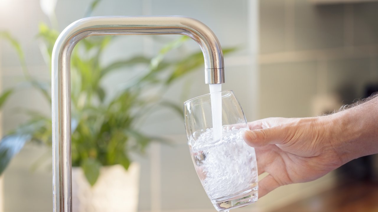 Bild zeigt ein Glas unter einem Wasserhahn