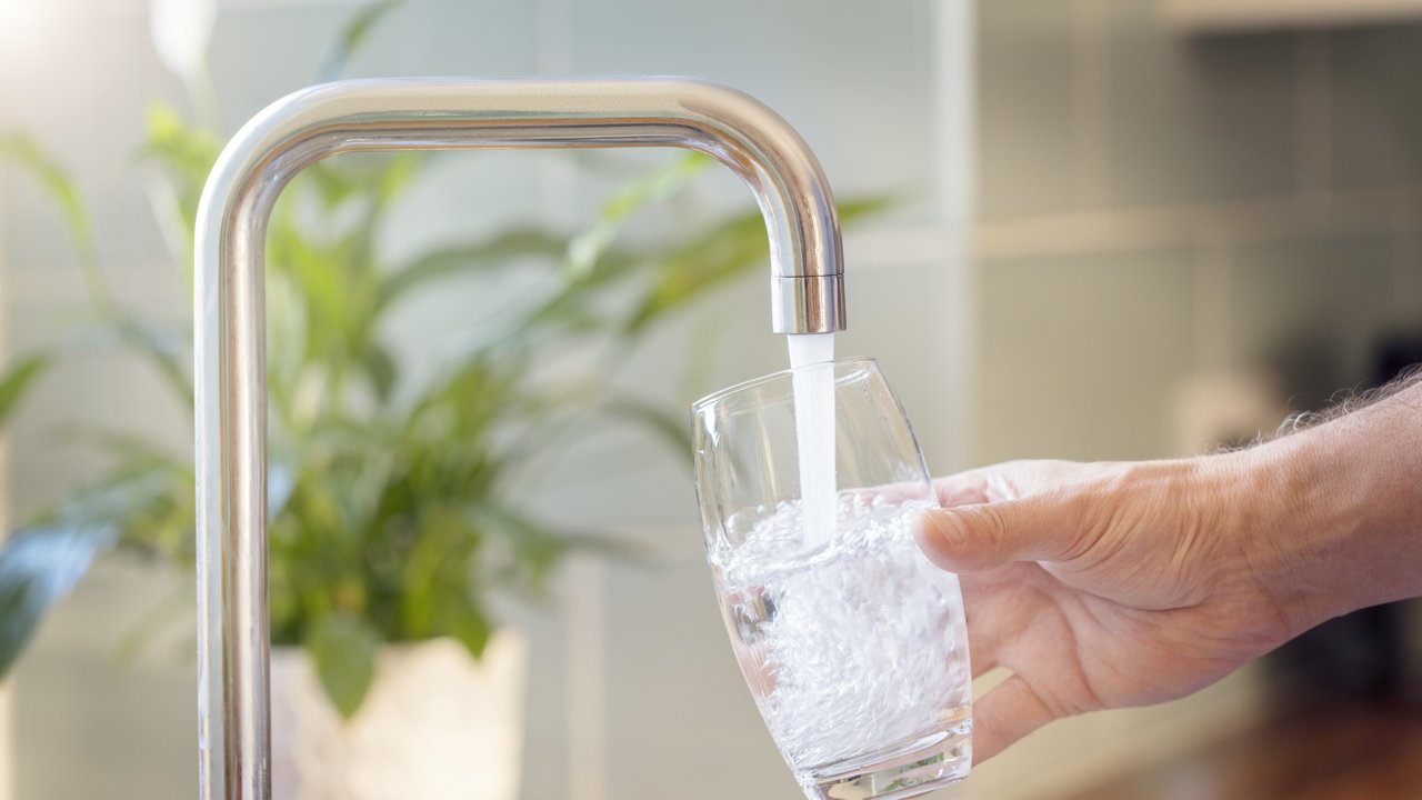 Bild zeigt ein Glas unter einem Wasserhahn