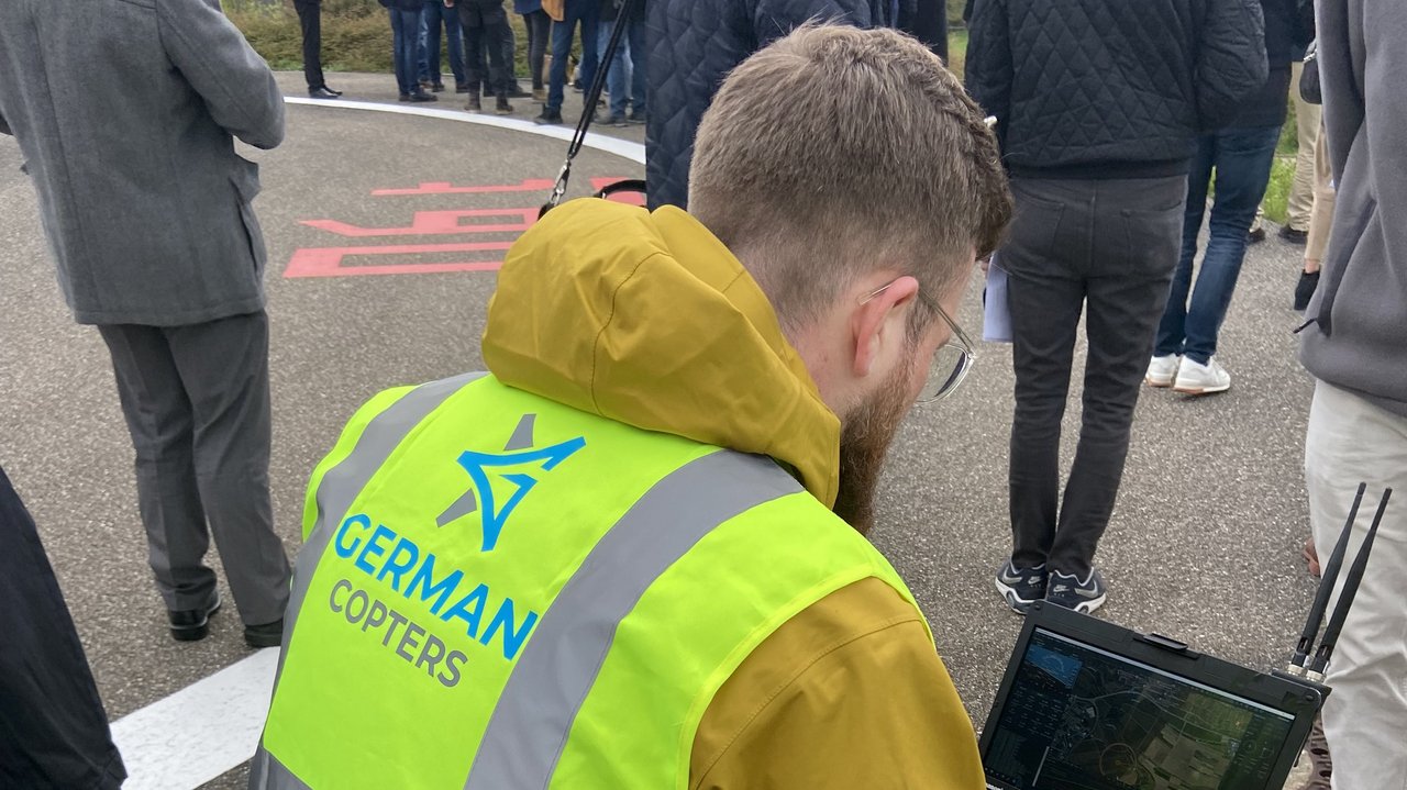 Ein Mitarbeiter sitzt auf einer Metallkiste mit einem Laptop und überwacht den Drohnenflug