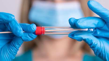 Krankenschwester mit Schutzmaske hält einen Virus-Testkit