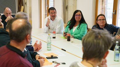 Mehrere Personen sitzen im Gespräch um einen Tisch