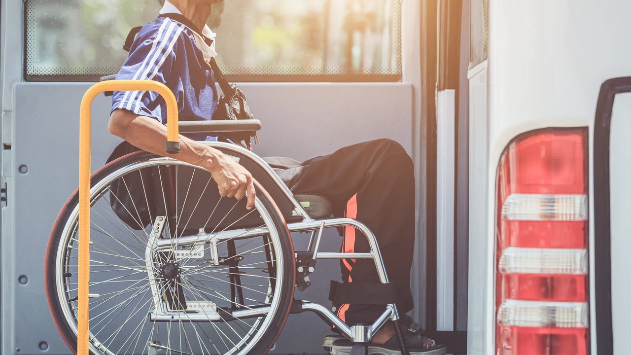 Rollstuhlfahrer der mit einer Hebebühne den Bus besteigen kann