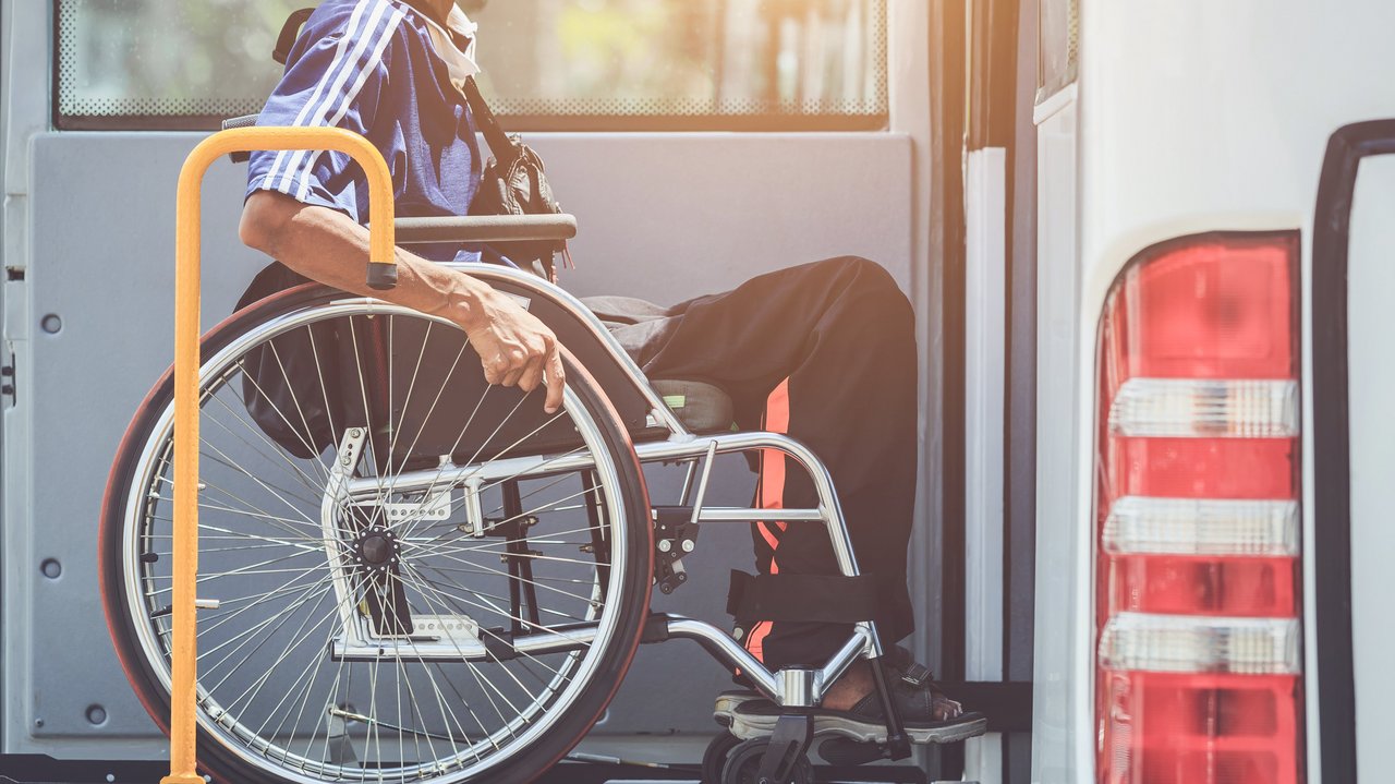 Rollstuhlfahrer der mit einer Hebebühne den Bus besteigen kann