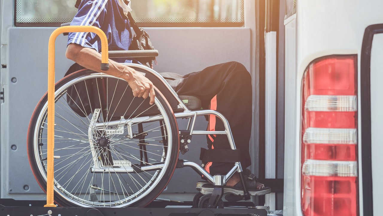 Rollstuhlfahrer der mit einer Hebebühne den Bus besteigen kann