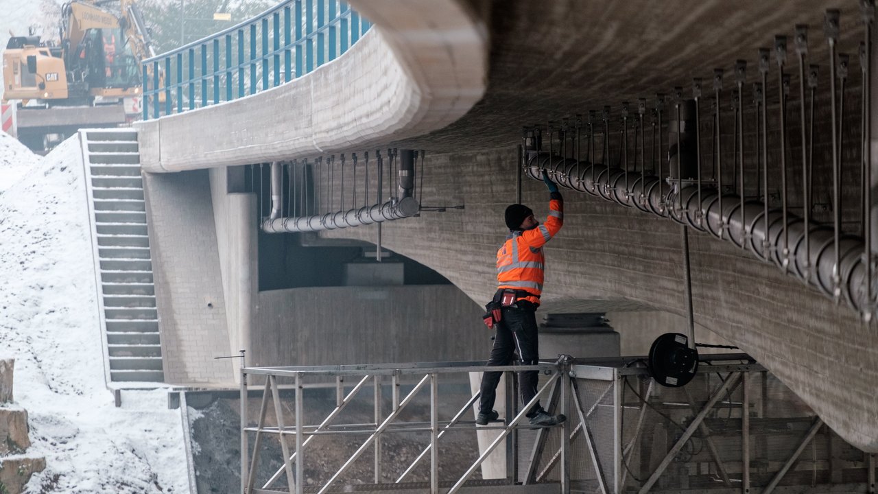 Prüfung einer Brücke: Ein Ingenieur steht auf einem Hubwagen und kontrolliert die Brücke