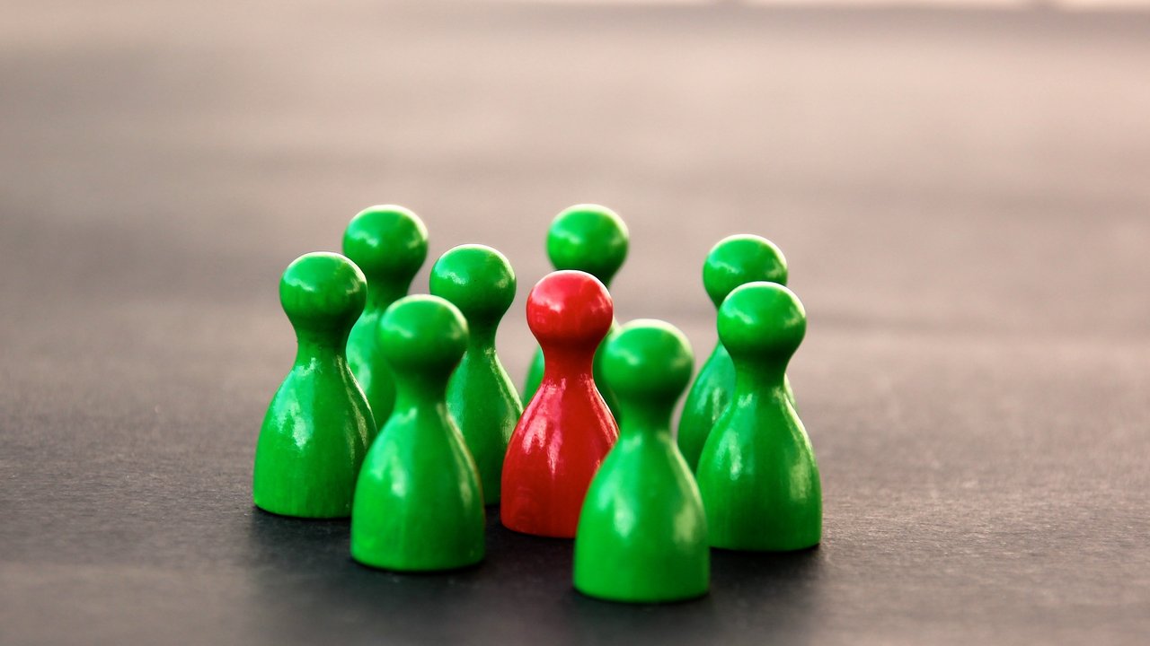 Ein roter Spielstein wird umgeben von mehreren grünen Spielsteinen