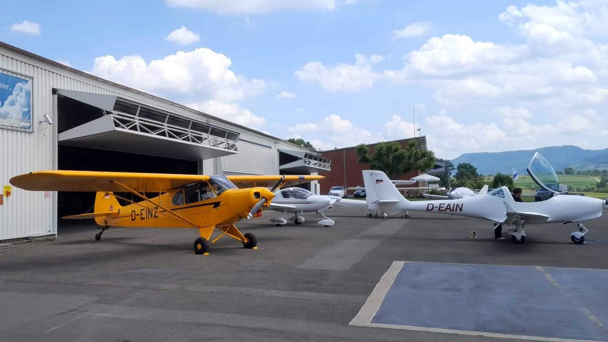 Kleinflugzeuge stehen vor einem Hangar
